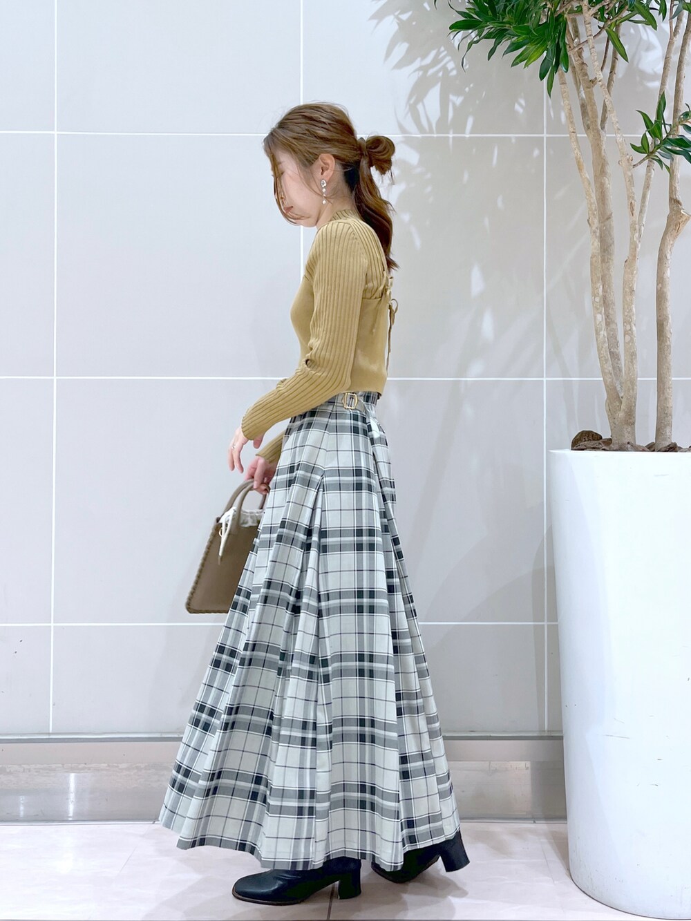 グリーン系のスカート、ブラック系のブーツ、ブラウン系のショルダーバッグを着用したレディースの秋コーディネートの3枚目の写真