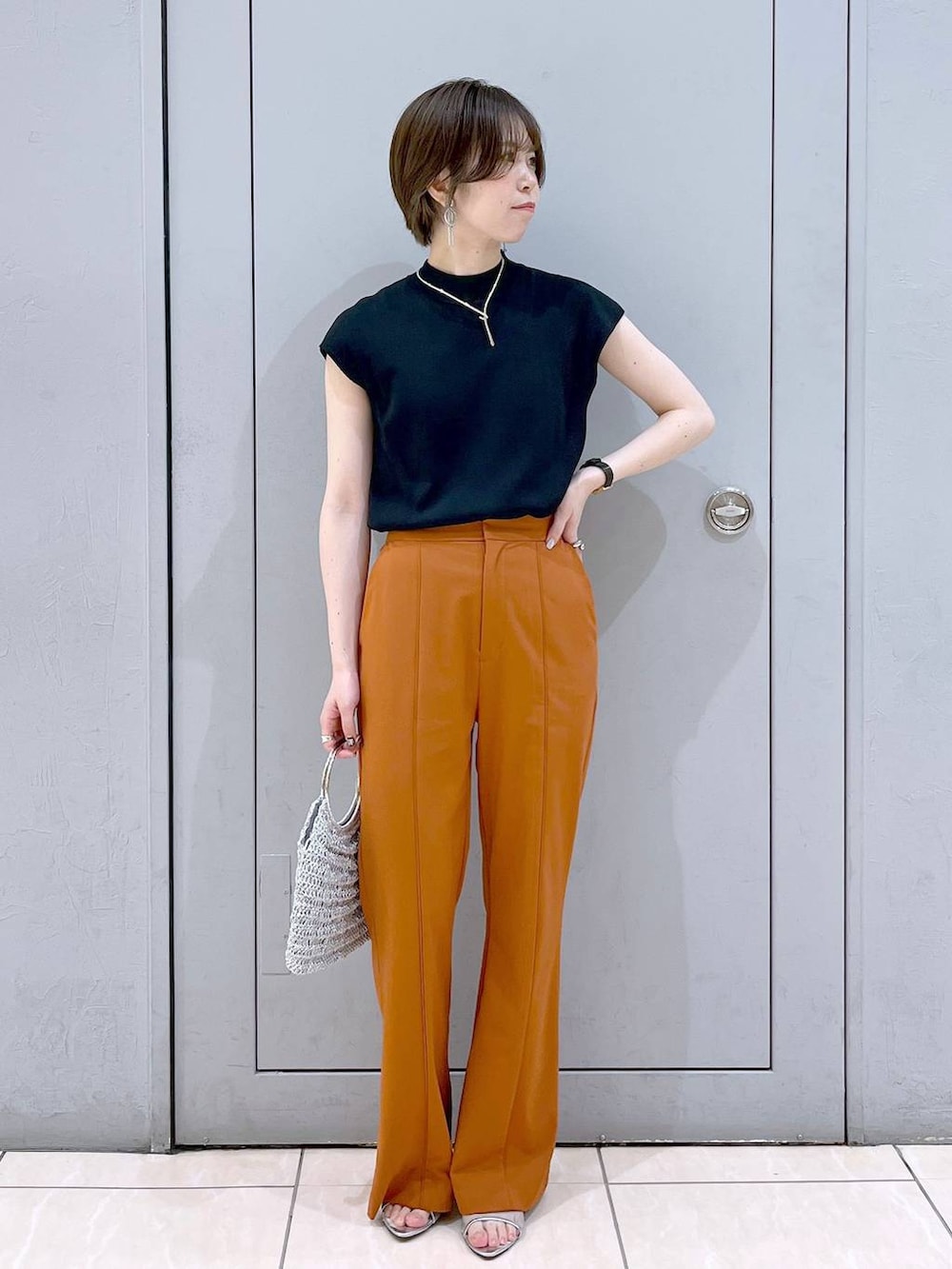 ブラック系のニット/セーター、シルバー系のハンドバッグ、シルバー系のサンダルを着用したレディースの夏コーディネートの2枚目の写真