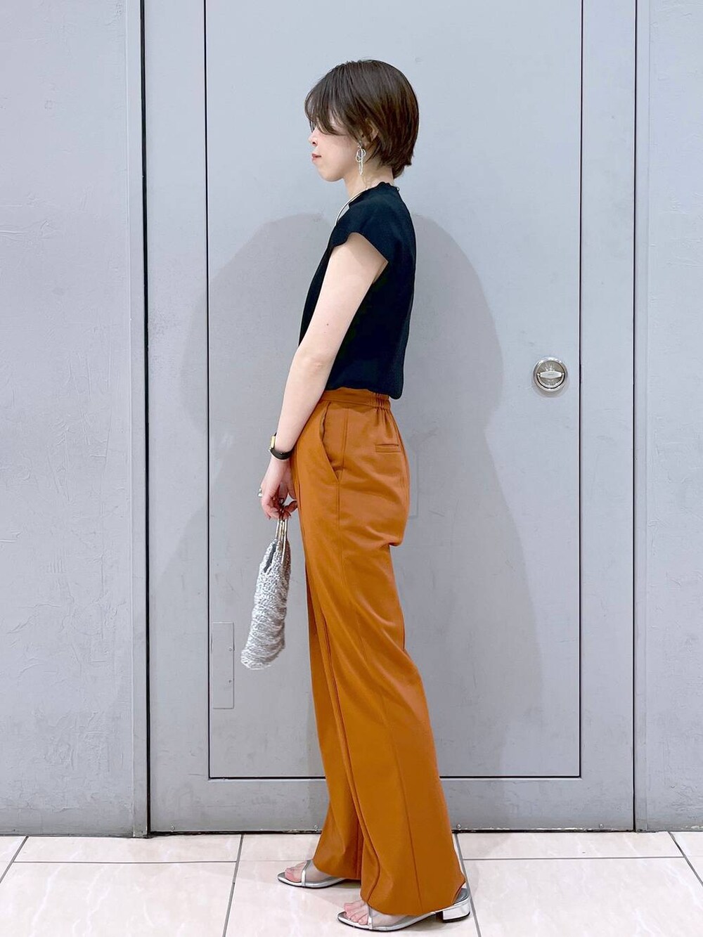 ブラック系のニット/セーター、シルバー系のハンドバッグ、シルバー系のサンダルを着用したレディースの夏コーディネートの3枚目の写真