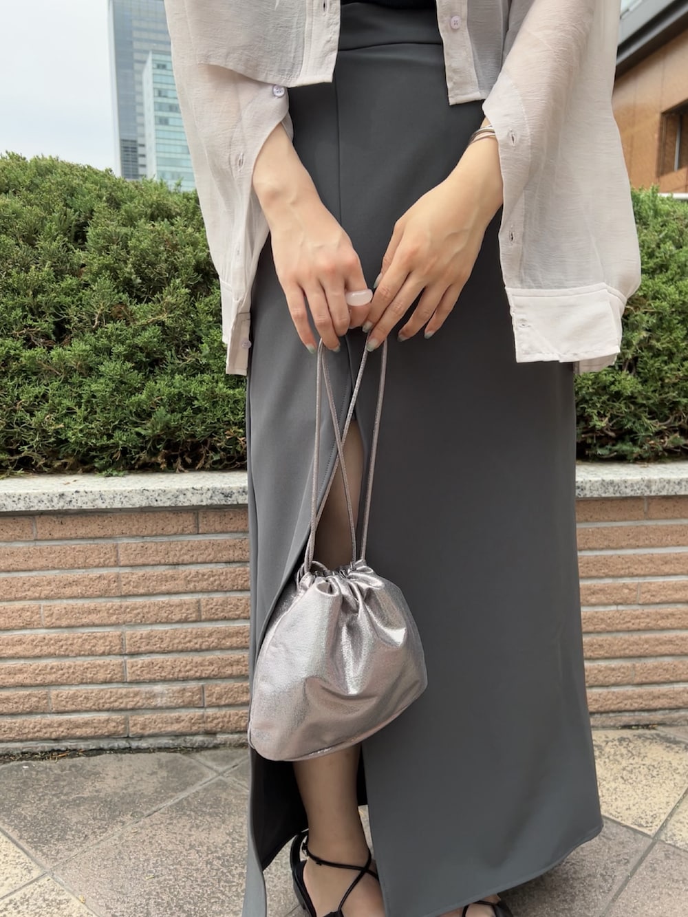ホワイト系のシャツ/ブラウス、ゴールド系のショルダーバッグ、ブラック系のスカートを着用したレディースの夏コーディネートの2枚目の写真