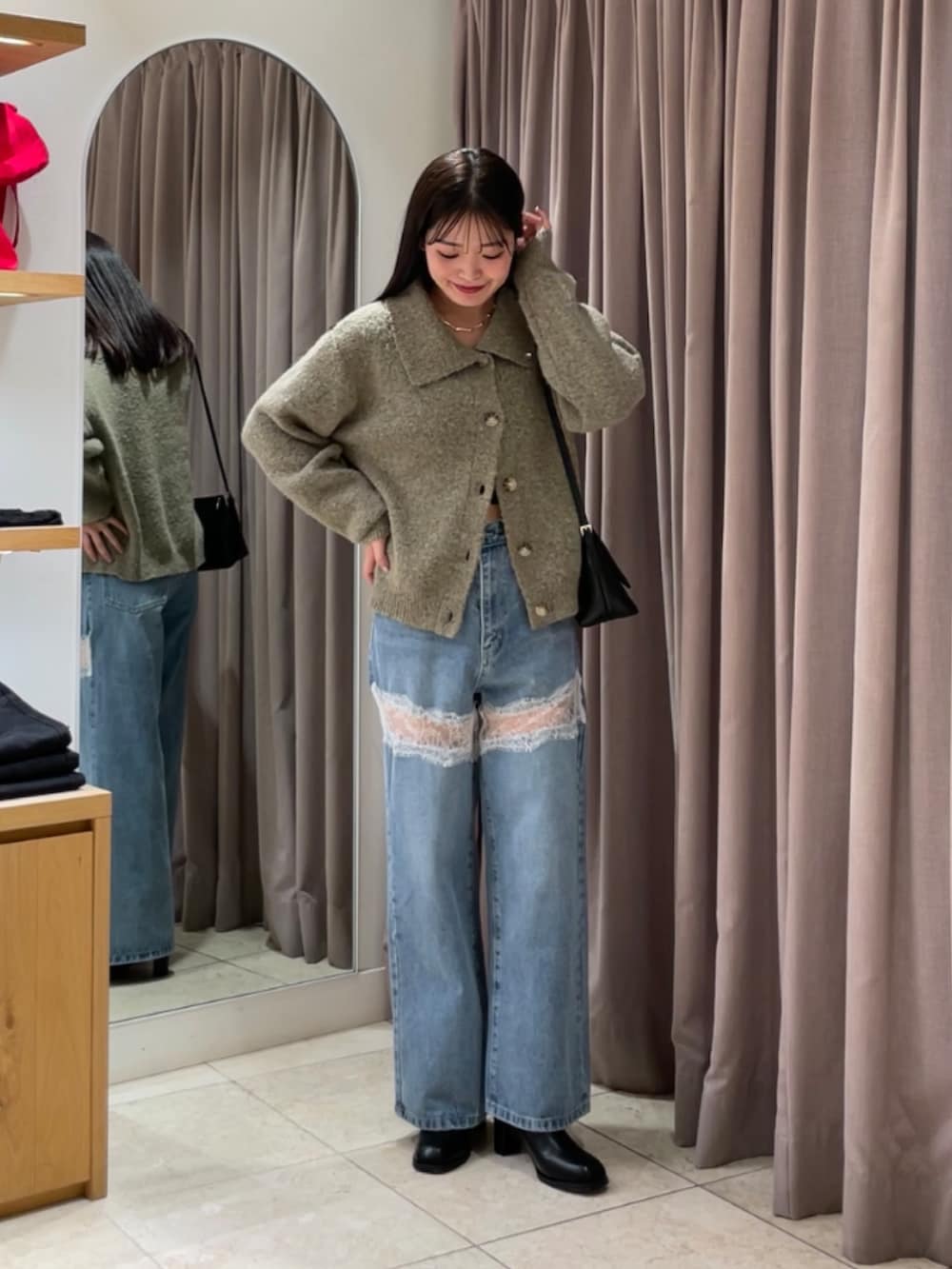 ブルー系のデニムパンツ、ブラック系のブーツ、ベージュ系のカーディガン/ボレロを着用したレディースの秋コーディネートの2枚目の写真