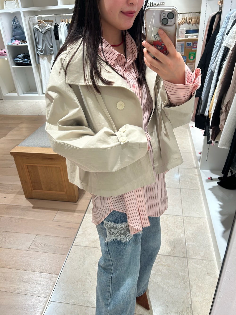 ピンク系のシャツ/ブラウス、ホワイト系のトレンチコート、ブルー系のデニムパンツを着用したレディースの冬コーディネートの2枚目の写真