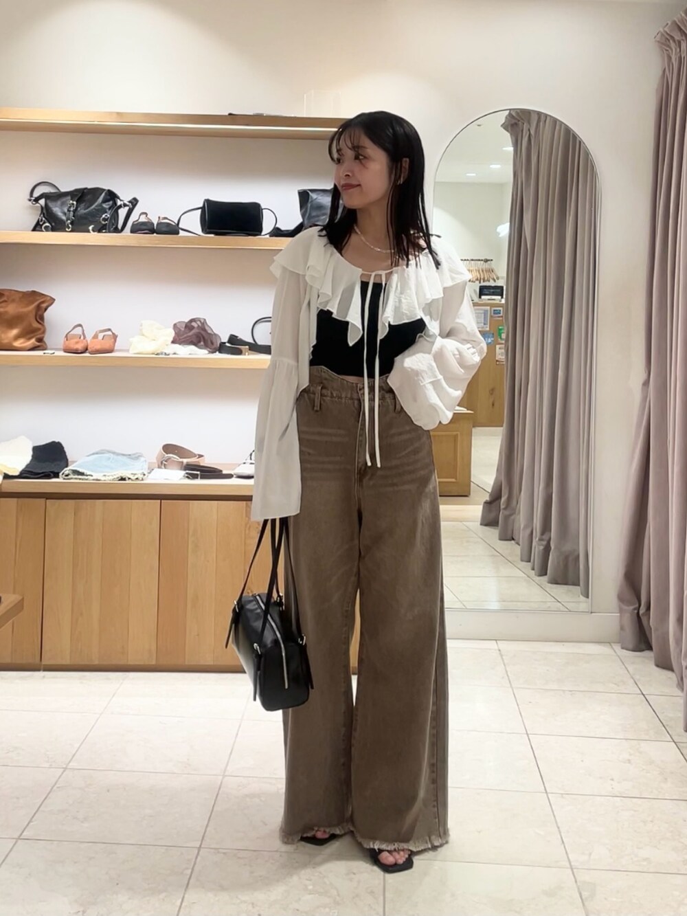 ブラック系のトートバッグ、ブラウン系のデニムパンツ、ブラック系のキャミソールを着用したレディースの夏コーディネートの3枚目の写真