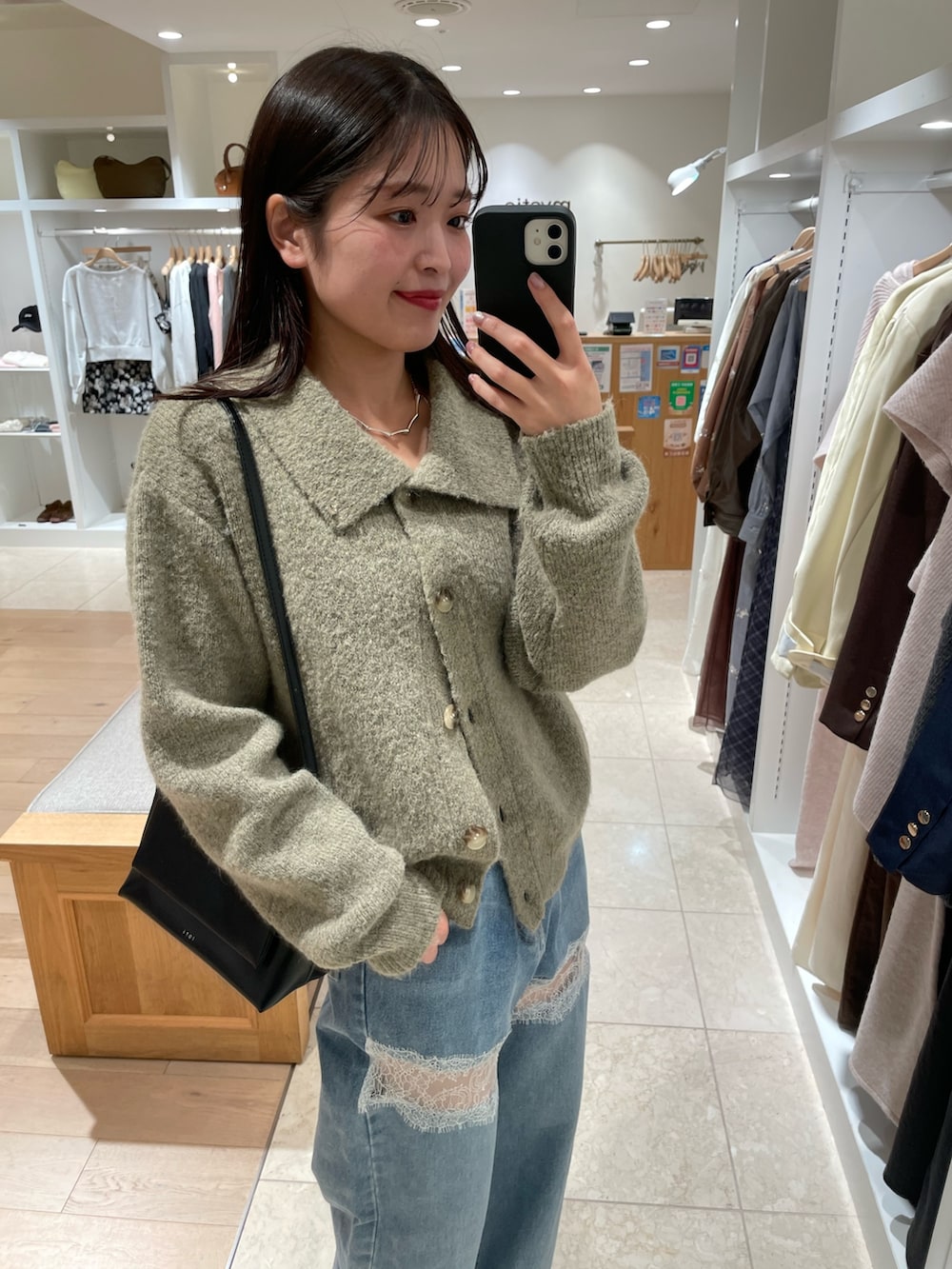 ブルー系のデニムパンツ、ブラック系のブーツ、ベージュ系のカーディガン/ボレロを着用したレディースの秋コーディネートの3枚目の写真