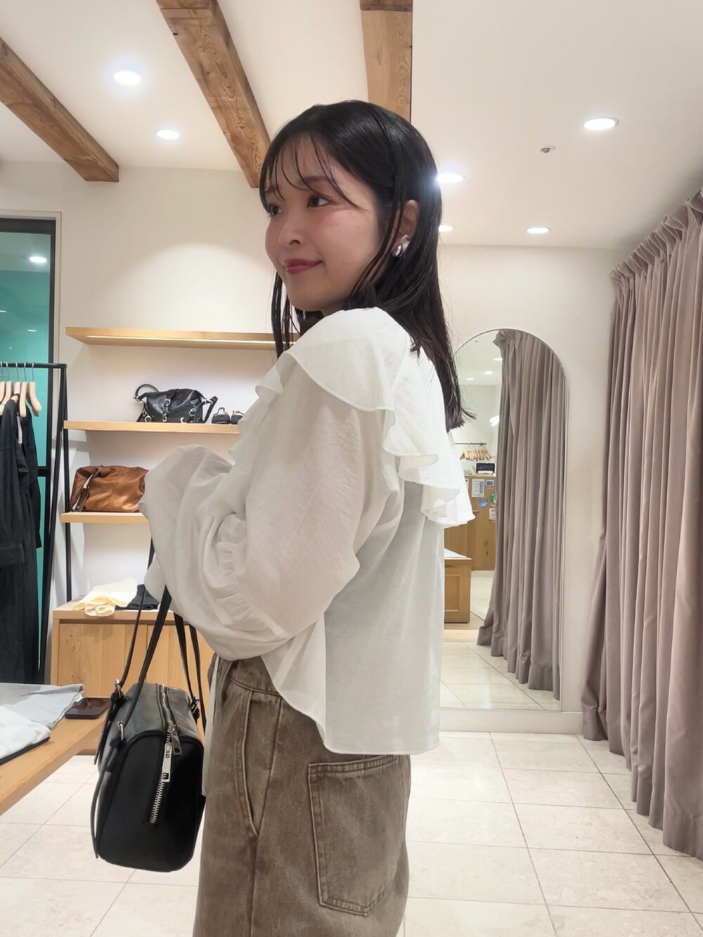 ブラック系のトートバッグ、ブラウン系のデニムパンツ、ブラック系のキャミソールを着用したレディースの夏コーディネートの2枚目の写真