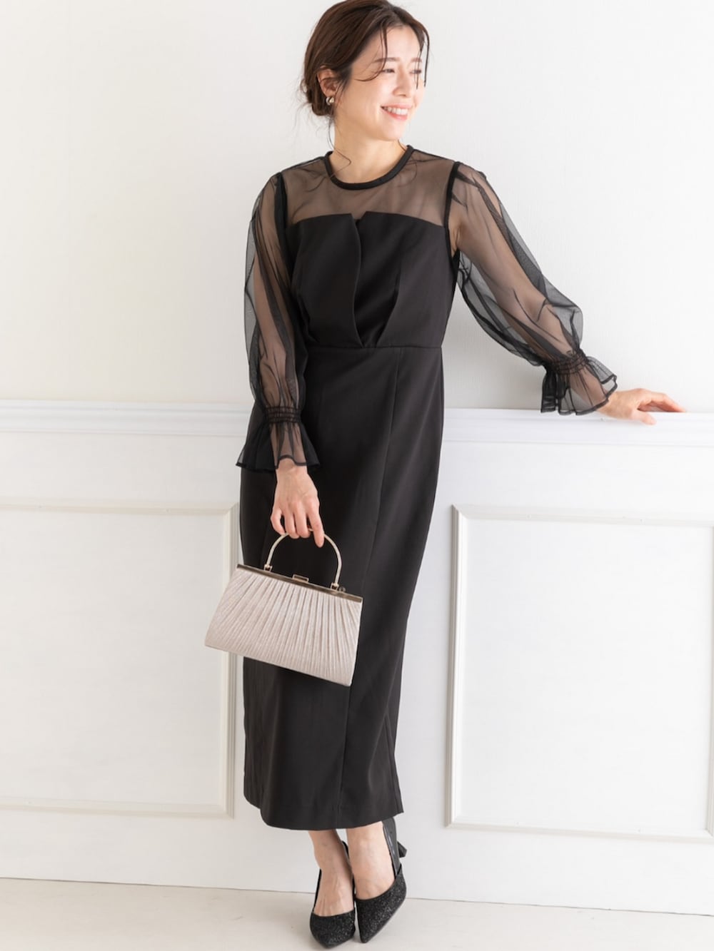 ベージュ系のクラッチバッグ、ブラック系のドレスを着用したレディースの春コーディネートの2枚目の写真