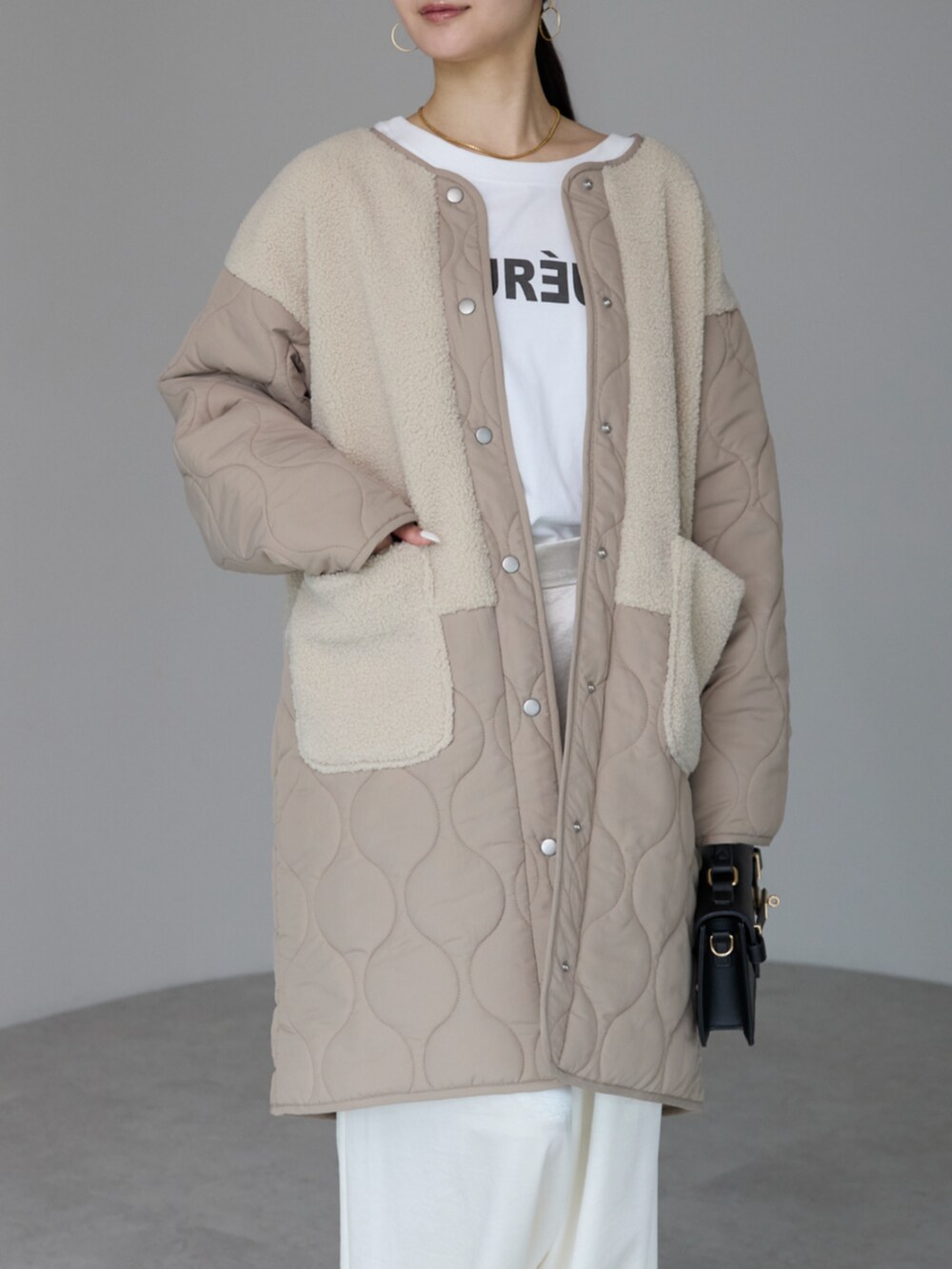 ベージュ系のノーカラーコートを着用したレディースの冬コーディネートの2枚目の写真