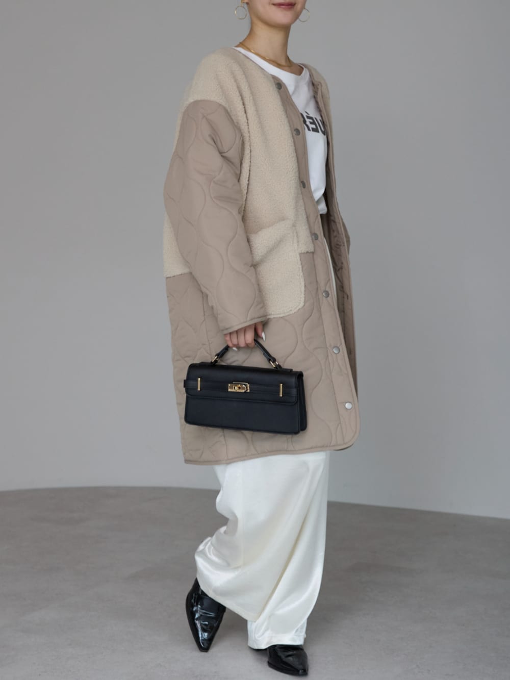 ベージュ系のノーカラーコートを着用したレディースの冬コーディネートの3枚目の写真