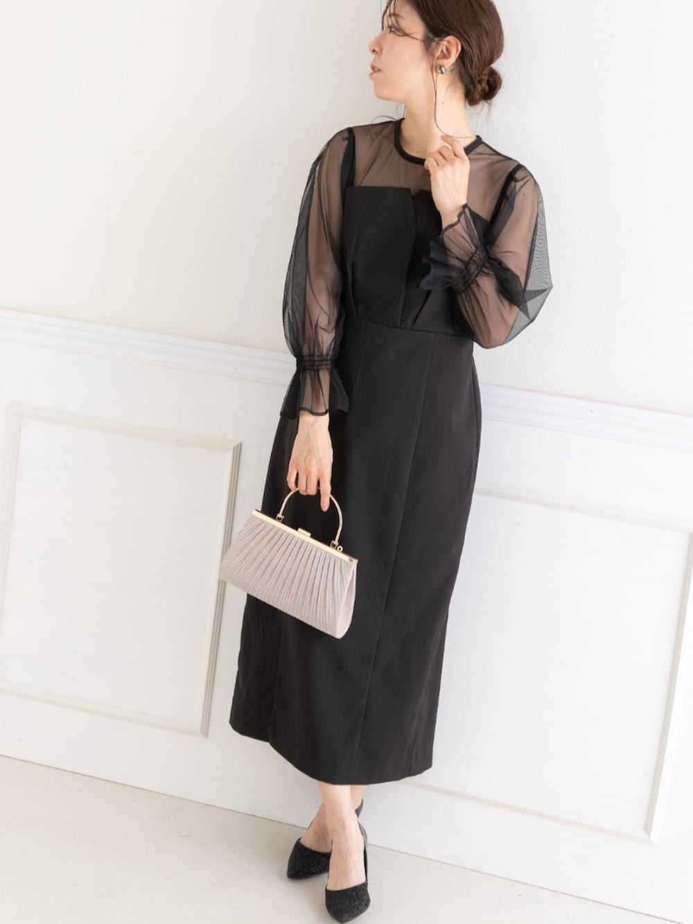 ベージュ系のクラッチバッグ、ブラック系のドレスを着用したレディースの春コーディネートの3枚目の写真