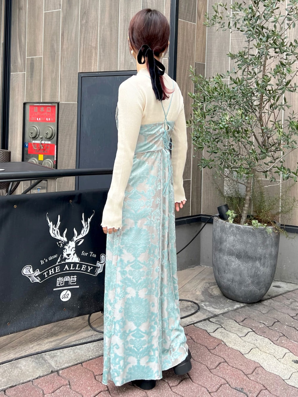 グリーン系のワンピース、ホワイト系のニット/セーター、ホワイト系のブーツを着用したレディースの秋コーディネートの2枚目の写真