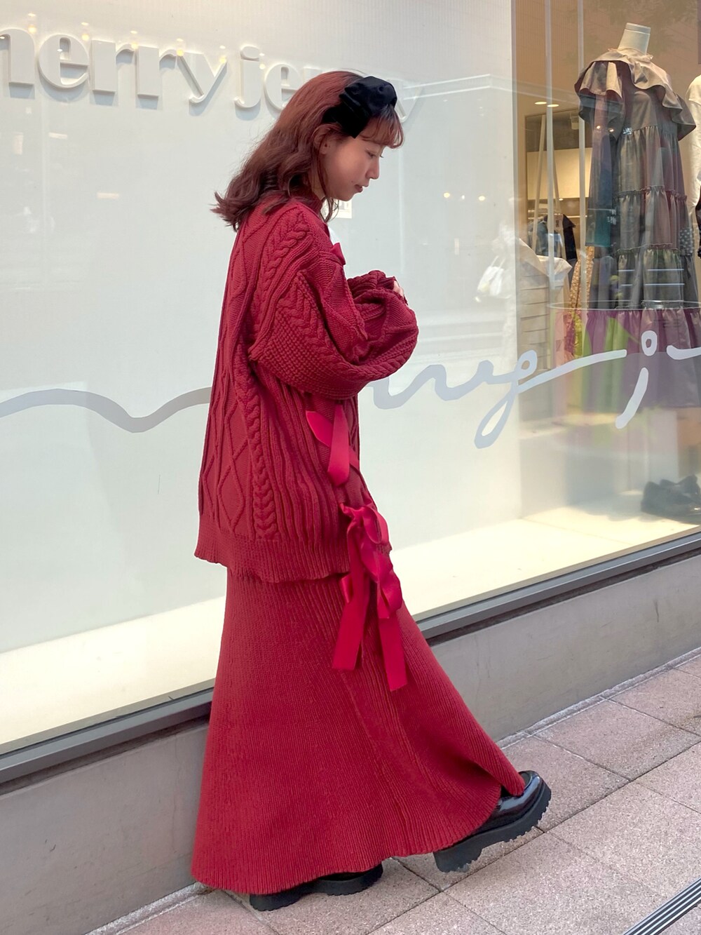 レッド系のニット/セーター、レッド系のスカート、ブラック系のローファーを着用したレディースの秋コーディネートの3枚目の写真