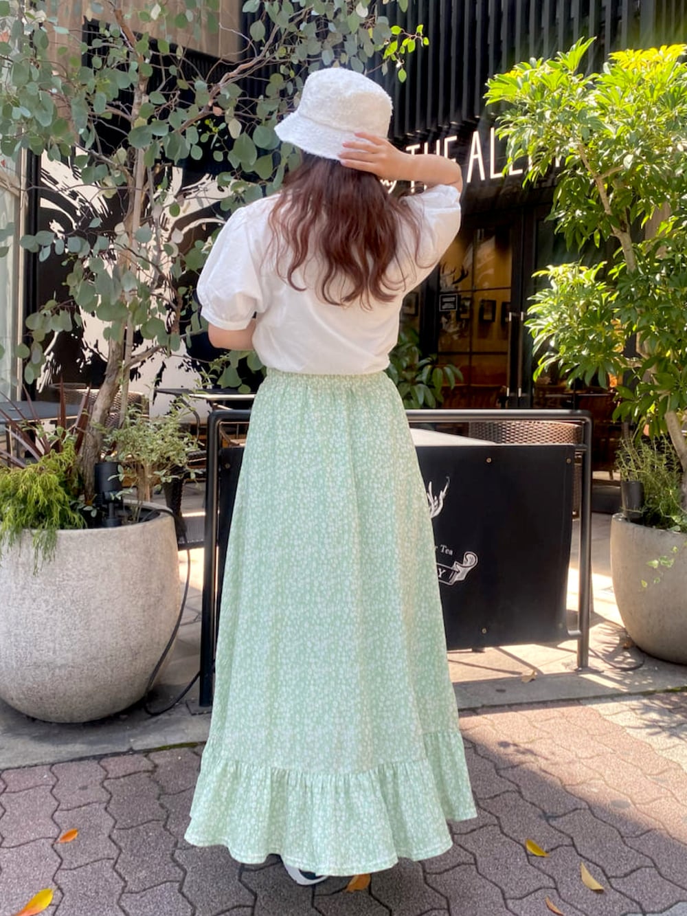 ホワイト系のトートバッグ、グリーン系のスカート、ホワイト系のサンダルを着用したレディースの夏コーディネートの2枚目の写真
