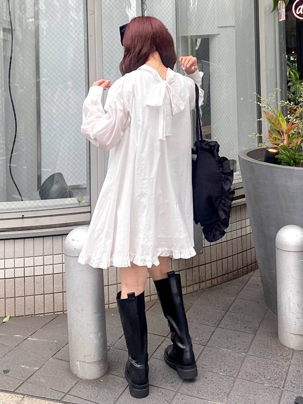 ホワイト系のワンピース、ブラック系のトートバッグ、ブラック系のブーツを着用したレディースの夏コーディネートの2枚目の写真