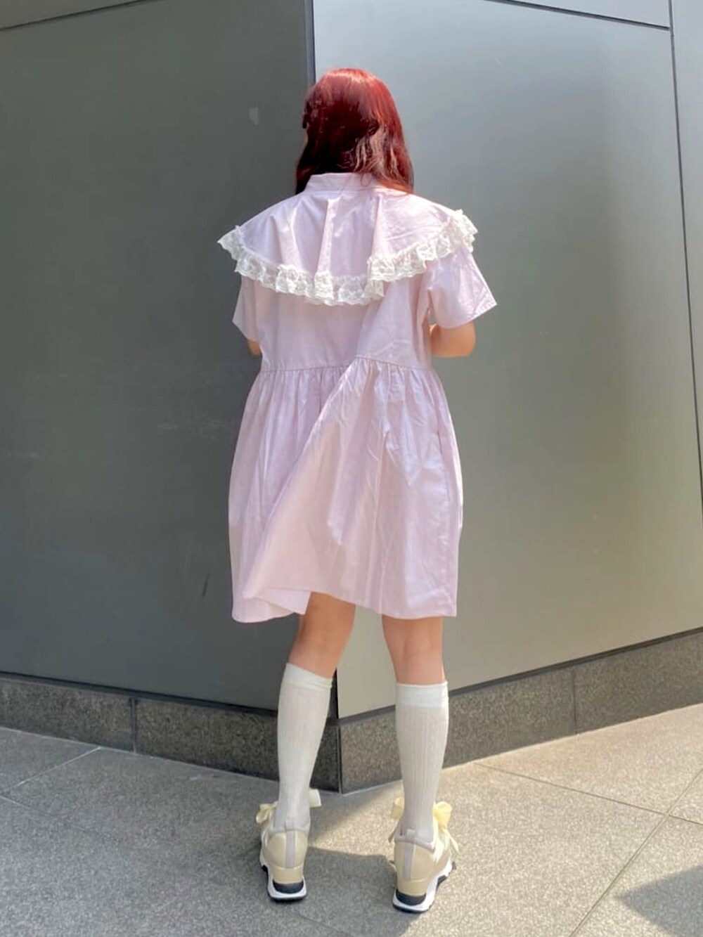 ピンク系のワンピース、ホワイト系のショルダーバッグ、ホワイト系のスニーカーを着用したレディースの夏コーディネートの2枚目の写真