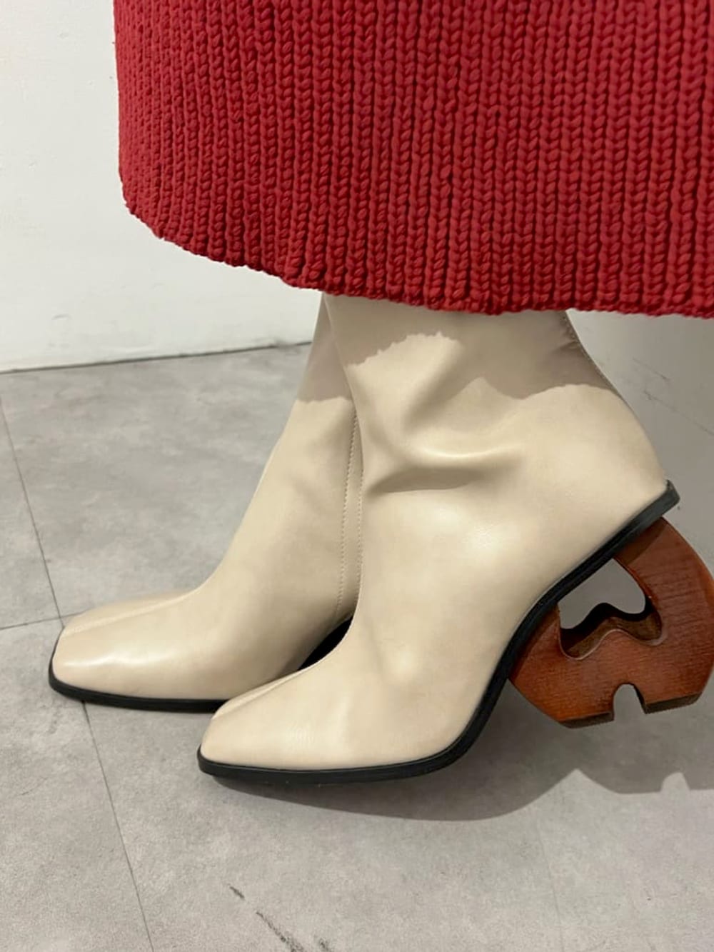 レッド系のニット/セーター、レッド系のスカート、ベージュ系のブーツを着用したレディースの秋コーディネートの3枚目の写真