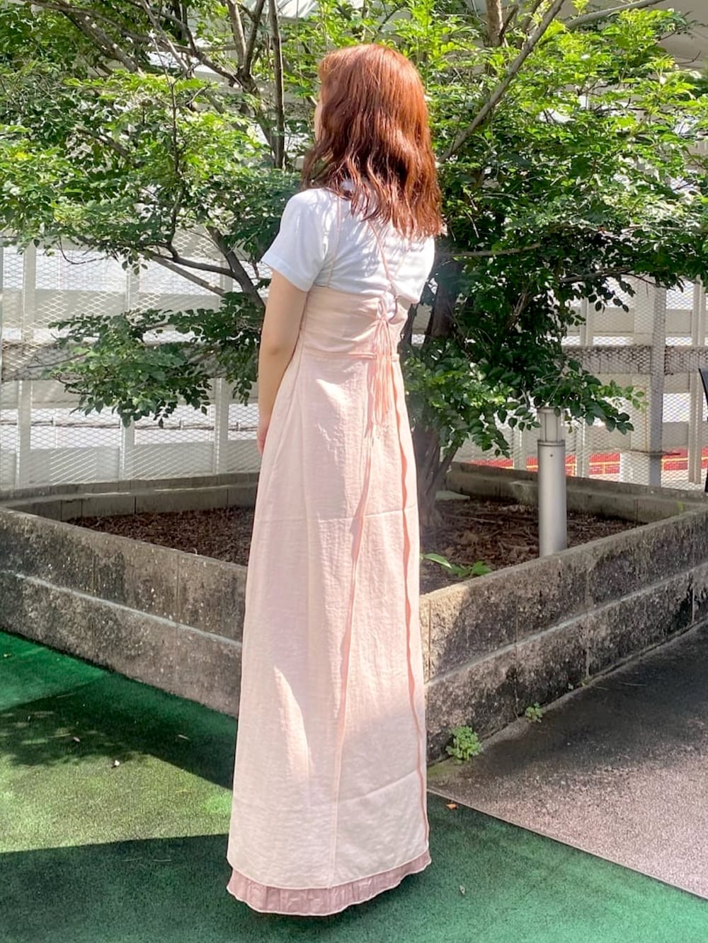 ピンク系のワンピース、ホワイト系のTシャツ/カットソー、パープル系のサンダルを着用したレディースの夏コーディネートの2枚目の写真