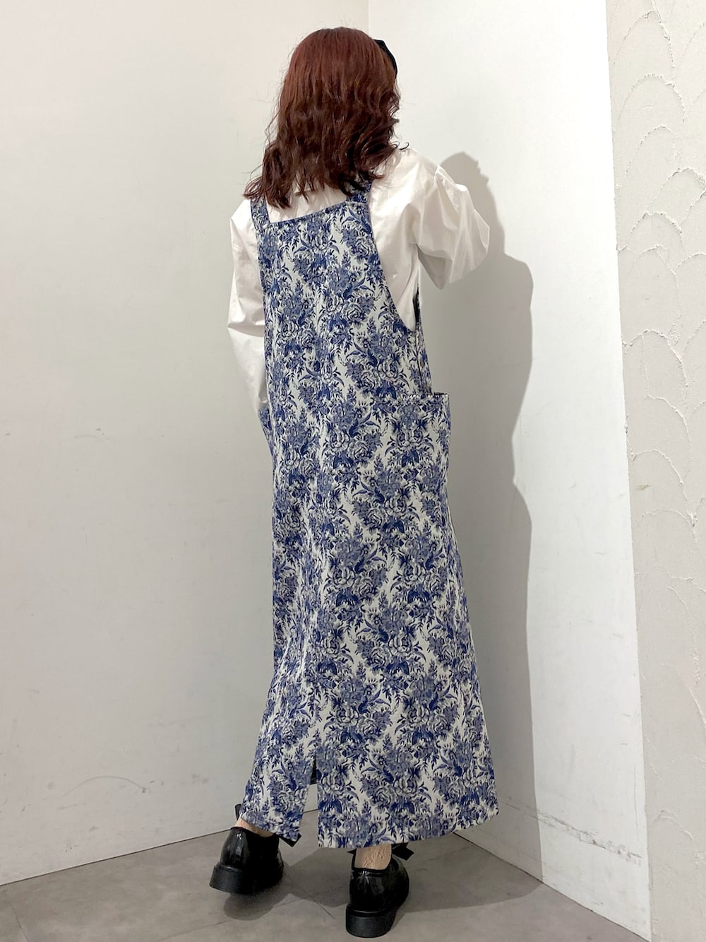 ブルー系のジャンパースカート、ブラック系のボストンバッグ、ホワイト系のシャツ/ブラウスを着用したレディースの秋コーディネートの2枚目の写真