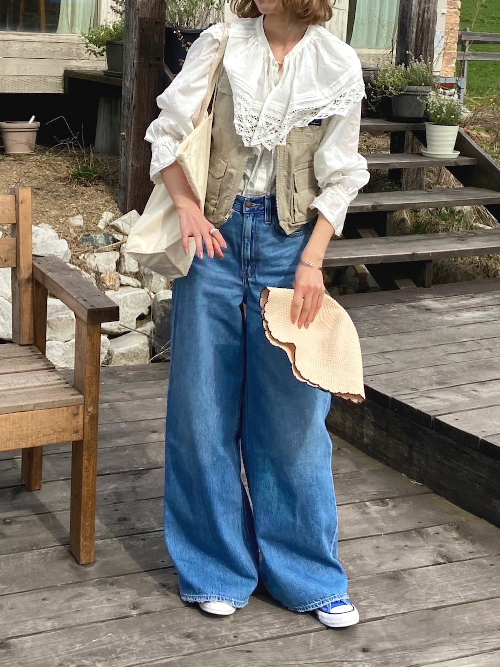 ホワイト系のシャツ/ブラウス、ベージュ系のベスト、ブルー系のデニムパンツを着用したレディースの春コーディネートの2枚目の写真