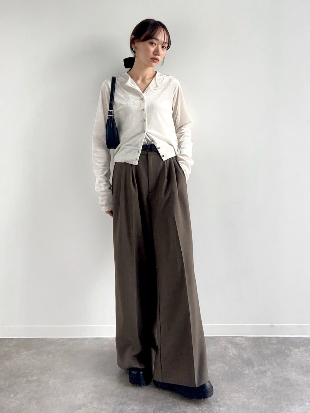 ホワイト系のカーディガン/ボレロ、ベージュ系のスラックス、ブラック系のハンドバッグを着用したレディースの冬コーディネートの2枚目の写真