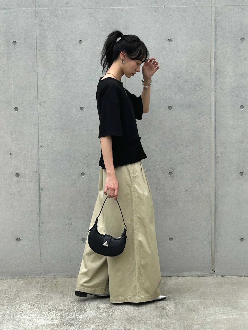 ブラック系のTシャツ/カットソー、ベージュ系のチノパンツ、ブラック系のハンドバッグを着用したレディースの夏コーディネートの2枚目の写真