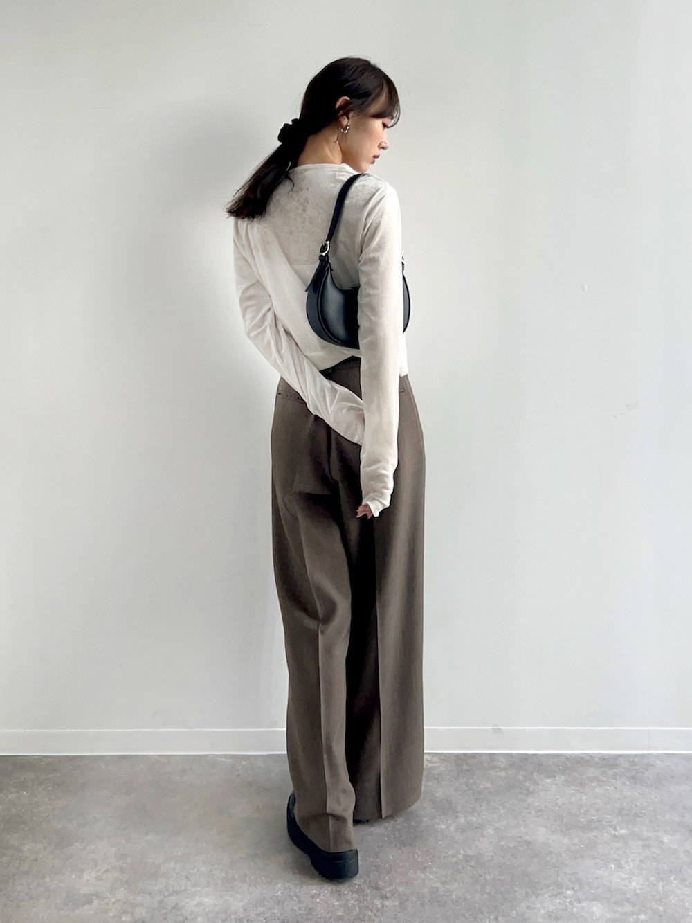 ホワイト系のカーディガン/ボレロ、ベージュ系のスラックス、ブラック系のハンドバッグを着用したレディースの冬コーディネートの3枚目の写真