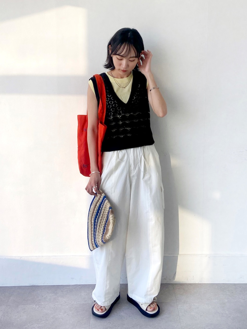イエロー系のTシャツ/カットソー、ブラック系のベスト、ホワイト系のカーゴパンツを着用したレディースの夏コーディネートの2枚目の写真