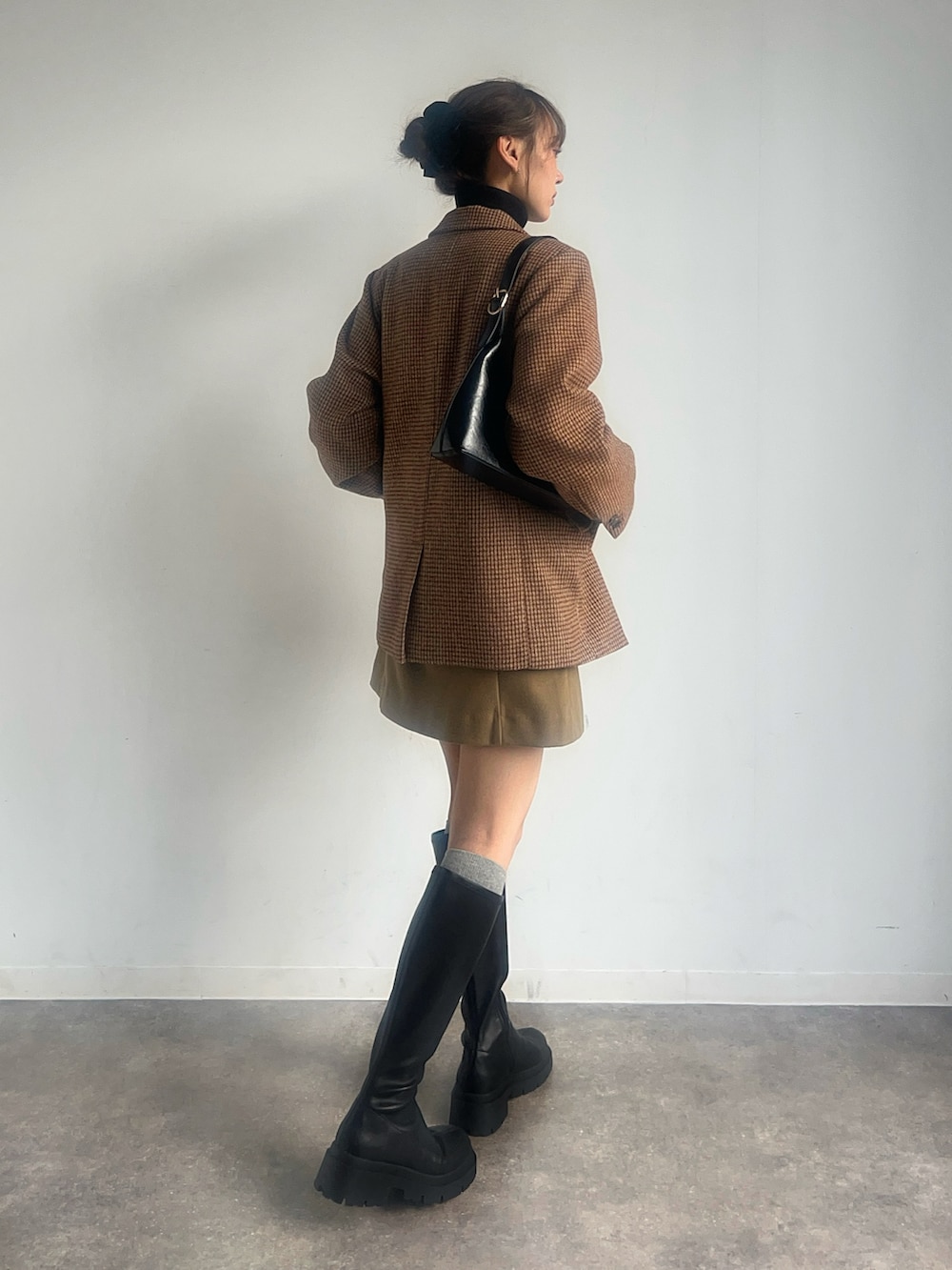 ブラック系のニット/セーター、ブラウン系のテーラードジャケット、ベージュ系のスカートを着用したレディースの冬コーディネートの2枚目の写真