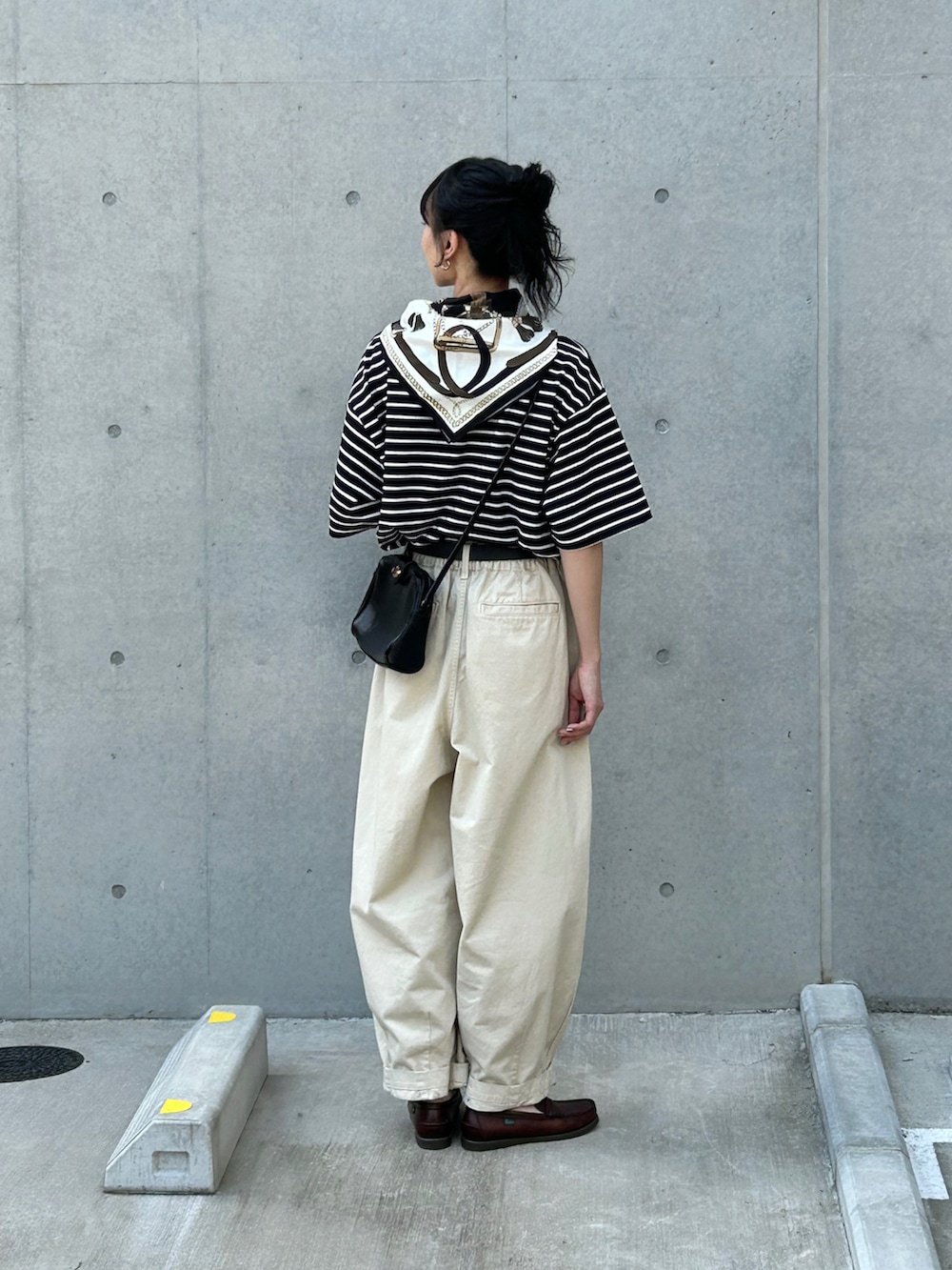 ブラック系のTシャツ/カットソー、ベージュ系のチノパンツ、ブラウン系のローファーを着用したレディースの春コーディネートの3枚目の写真