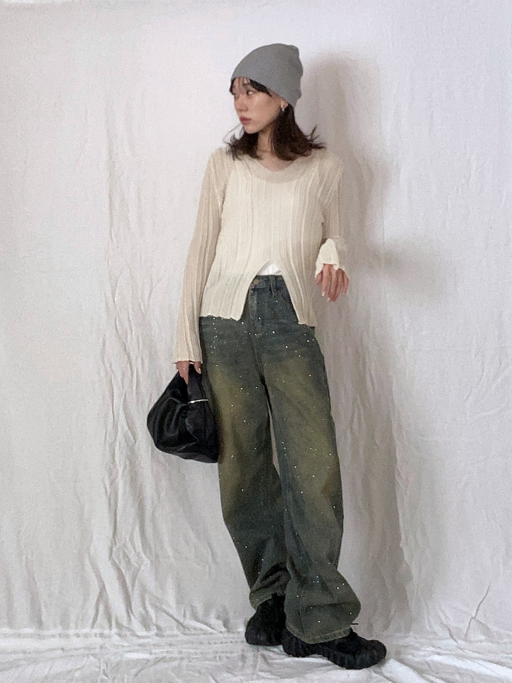 ベージュ系のニット/セーター、ブルー系のデニムパンツ、ブラック系のスニーカーを着用したレディースの春コーディネートの2枚目の写真