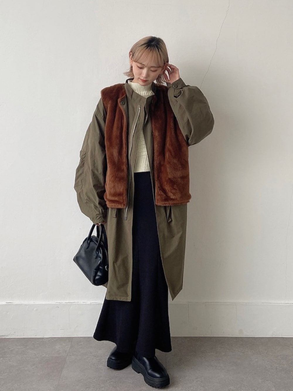 グリーン系のその他アウター、ホワイト系のニット/セーター、ブラック系のスカートを着用したレディースの冬コーディネートの2枚目の写真