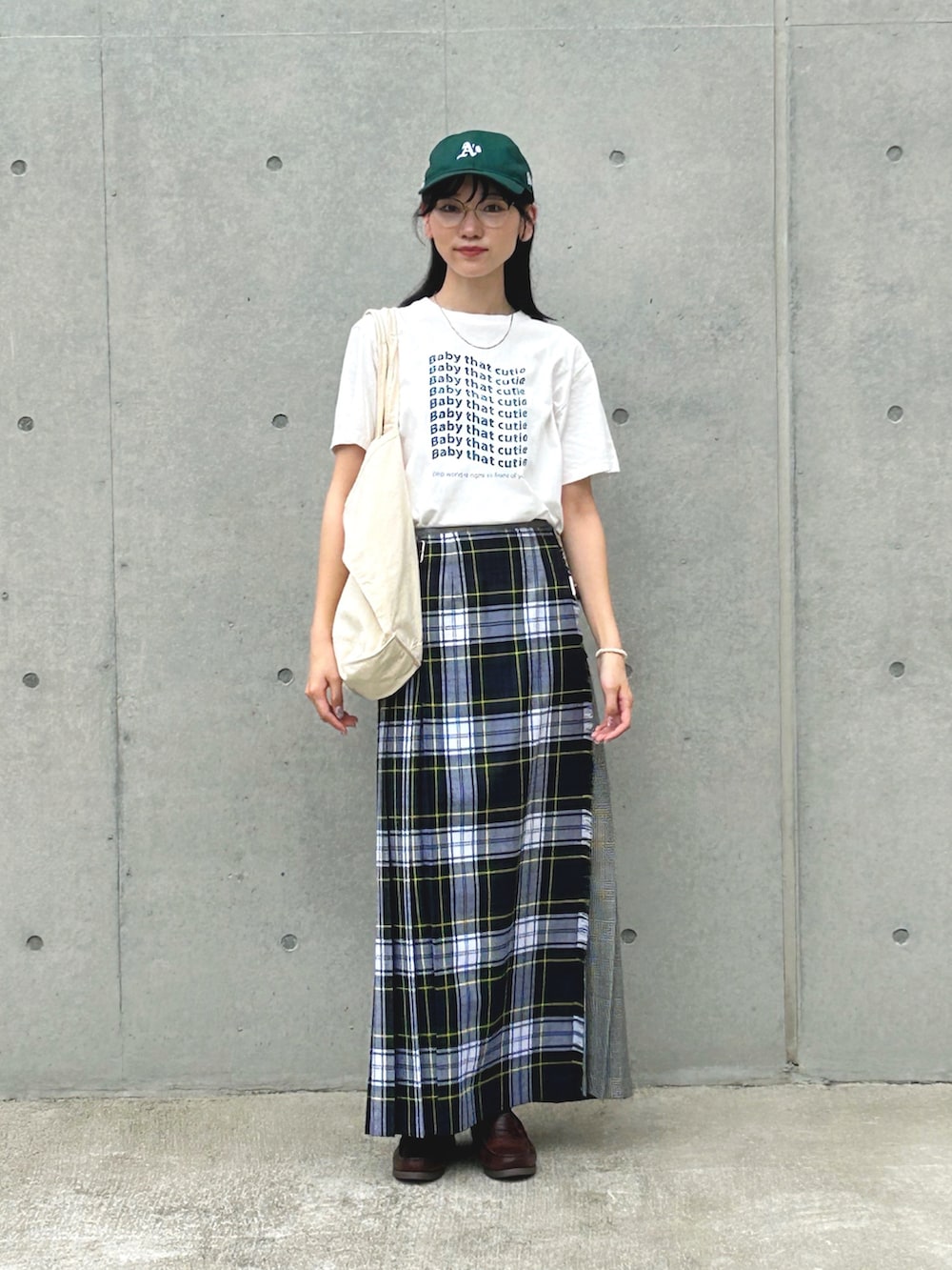 グリーン系のスカート、ホワイト系のTシャツ/カットソー、ホワイト系のトートバッグを着用したレディースの夏コーディネートの2枚目の写真