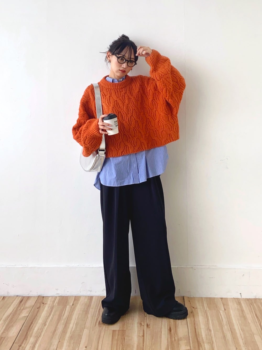 オレンジ系のニット/セーター、ブラック系のその他パンツ、シルバー系のショルダーバッグを着用したレディースの冬コーディネートの2枚目の写真