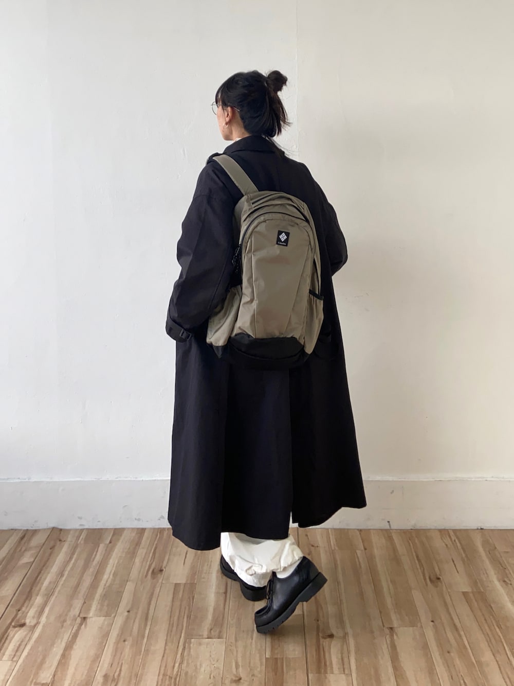 グレー系のニット/セーター、ブラック系のステンカラーコート、ホワイト系のTシャツ/カットソーを着用したレディースの秋コーディネートの3枚目の写真