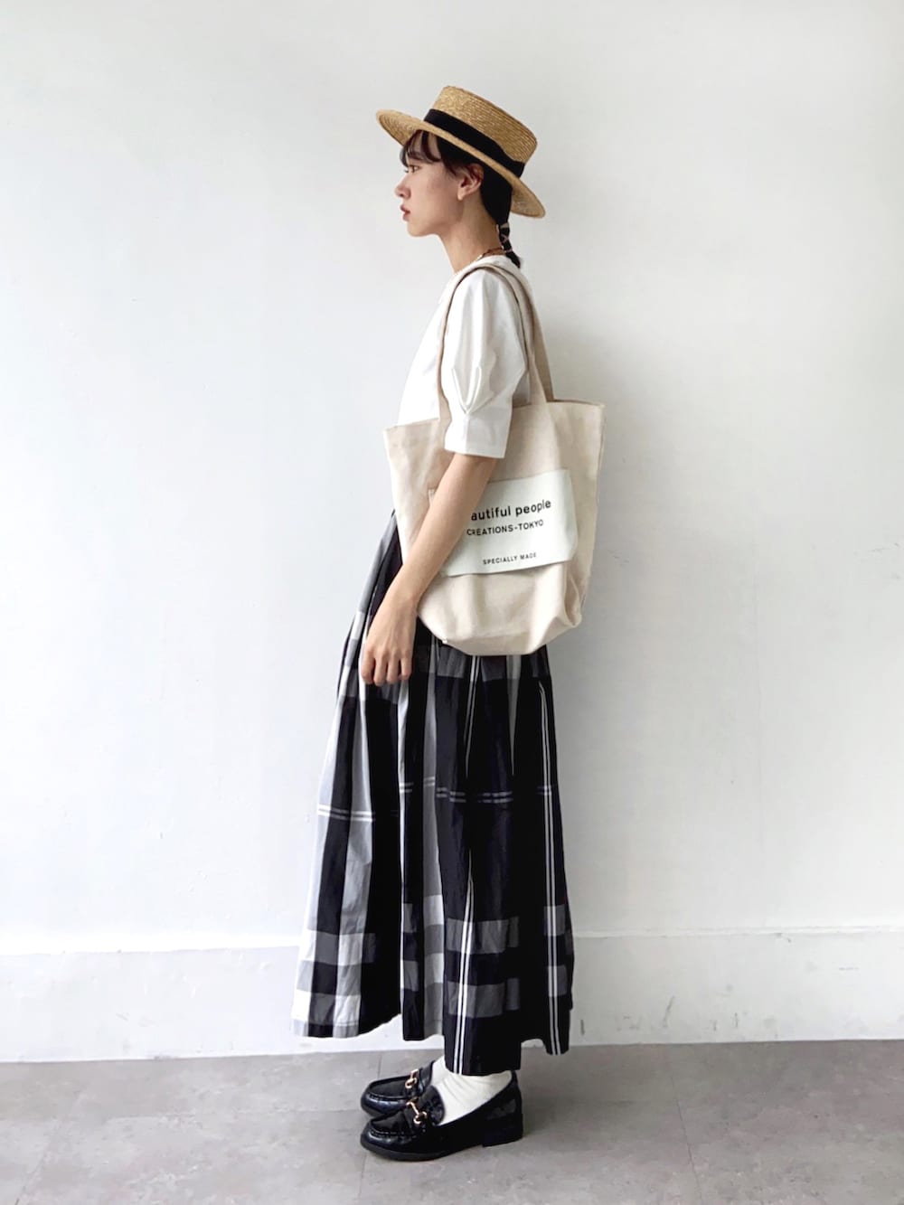 ホワイト系のトートバッグ、ブラック系のスカート、ベージュ系の帽子を着用したレディースの夏コーディネートの3枚目の写真