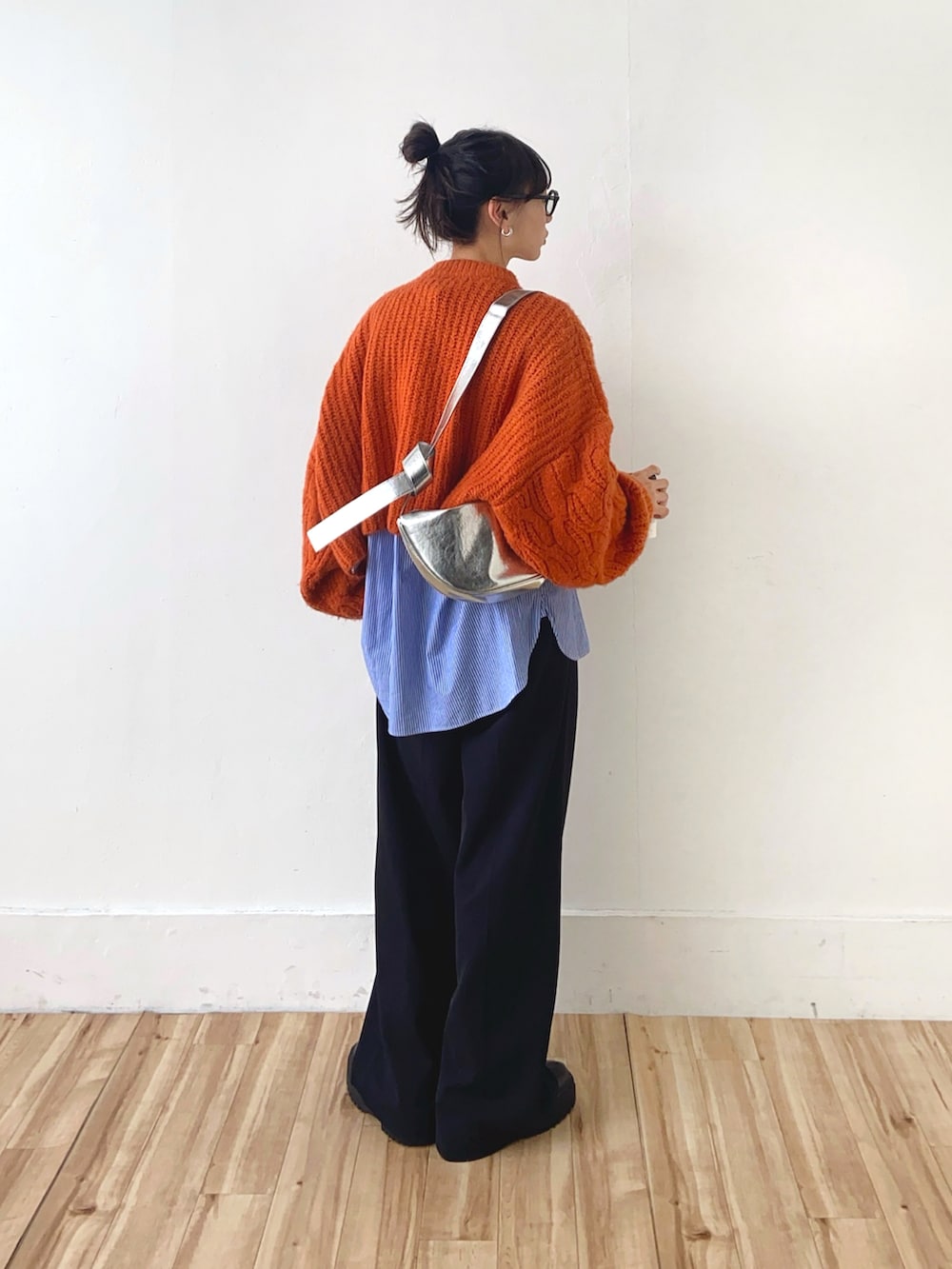 オレンジ系のニット/セーター、ブラック系のその他パンツ、シルバー系のショルダーバッグを着用したレディースの冬コーディネートの3枚目の写真