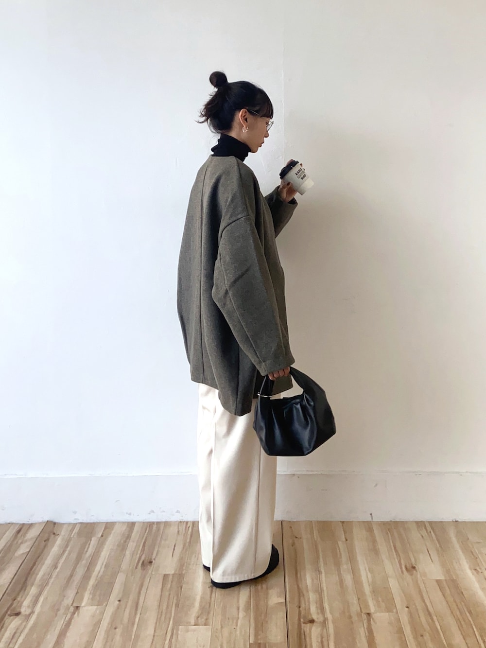 グレー系のノーカラーコート、ホワイト系のスラックス、ブラック系のショルダーバッグを着用したレディースの冬コーディネートの3枚目の写真