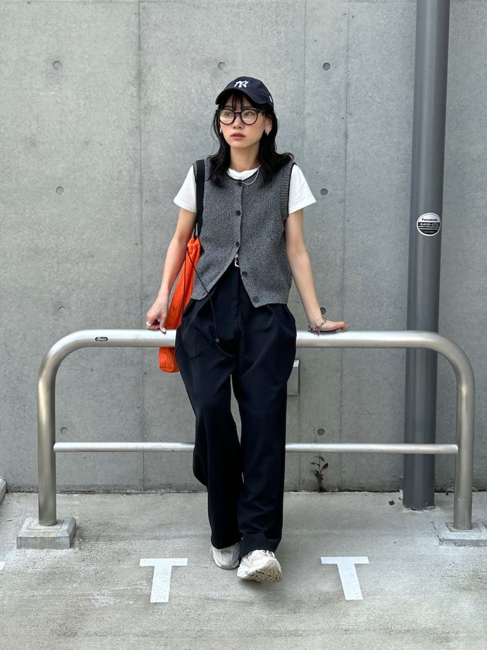 ブラック系のその他パンツ、ブラック系のベスト、オレンジ系のトートバッグを着用したレディースの春コーディネートの3枚目の写真