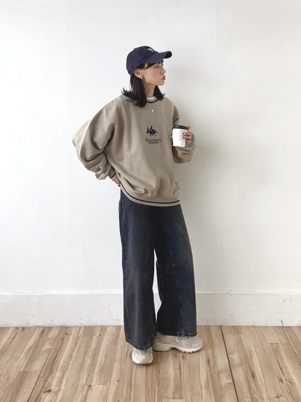 ベージュ系のスウェット、ブラック系のデニムパンツ、ブルー系のキャップを着用したレディースの冬コーディネートの3枚目の写真