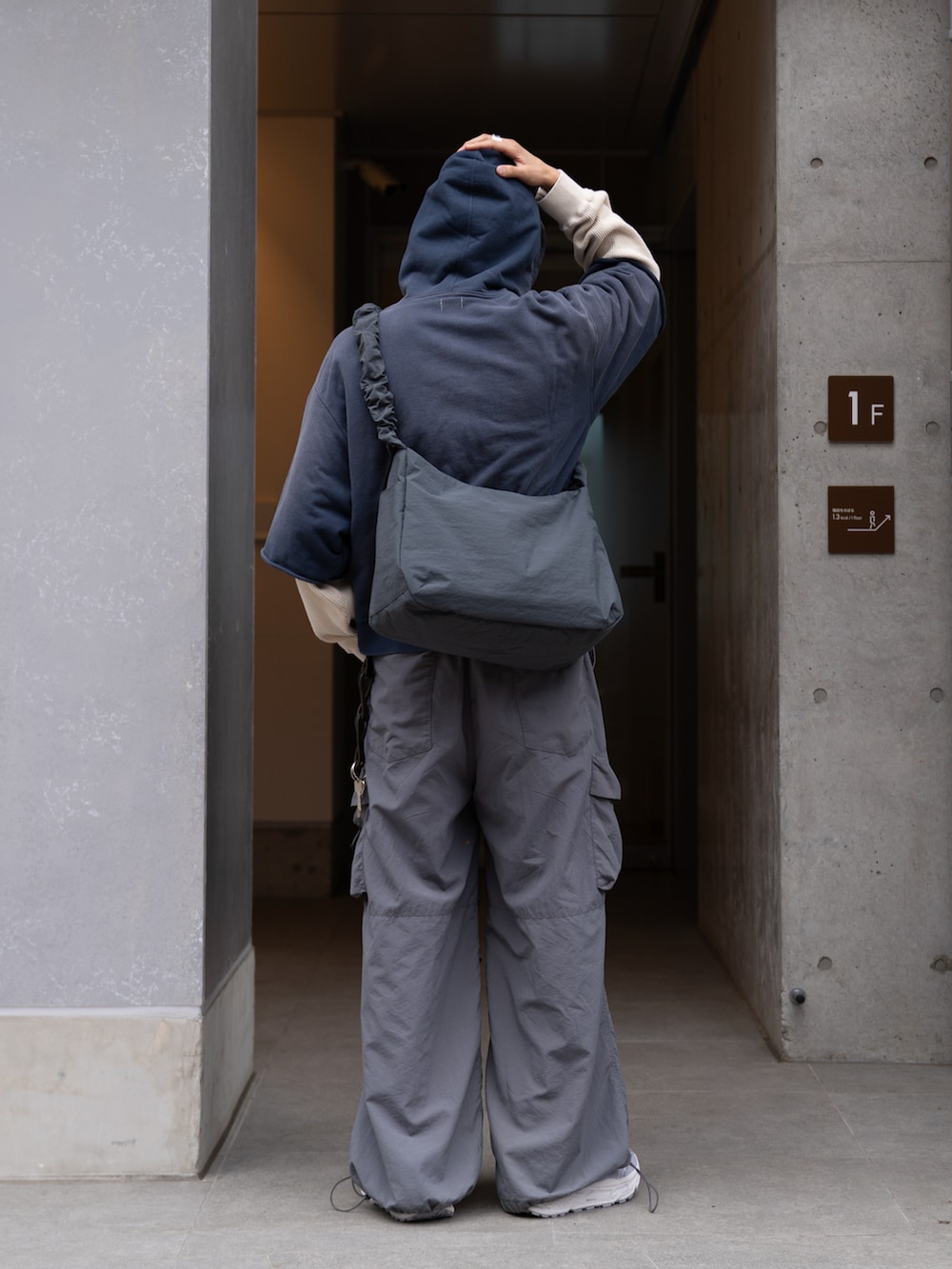 グレー系のカーゴパンツ、グレー系のショルダーバッグ、ブルー系のパーカーを着用したメンズの春コーディネートの3枚目の写真