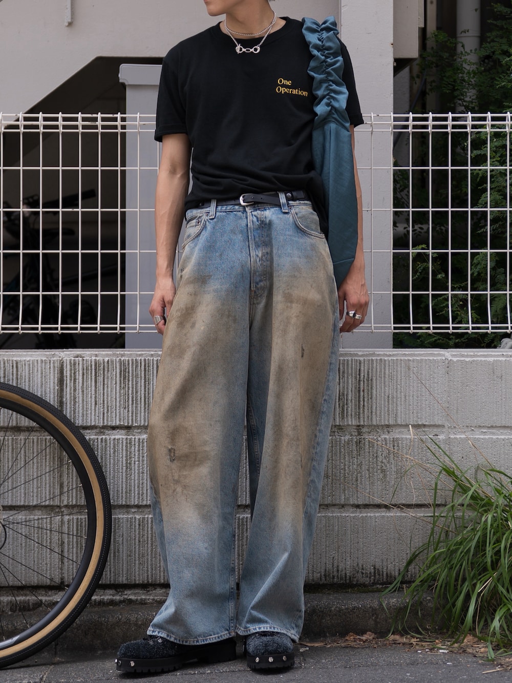 ブルー系のショルダーバッグ、ブラック系のTシャツ/カットソー、ブラック系のブーツを着用したメンズの夏コーディネートの3枚目の写真