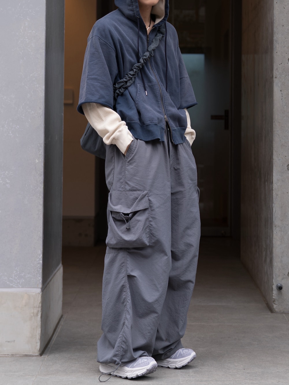 グレー系のカーゴパンツ、グレー系のショルダーバッグ、ブルー系のパーカーを着用したメンズの春コーディネートの4枚目の写真