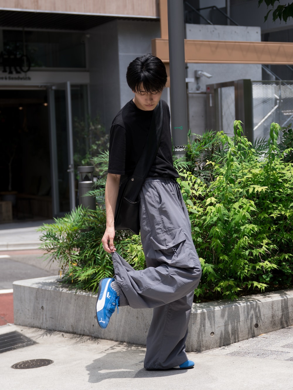 「ショルダーバッグ、夏コーデ、ワイドパンツ、カーゴパンツ、PUMA、黒Tシャツ、タックイン、シンプル、初夏コーデ、カジュアルコーデ」｜「WYM LIDNMのEXTRA FINE COTTON BASIC TEE -SLIM CROPPED FIT-（Tシャツ/カットソー、ブラック系）」を使った、KAIさん（メンズ・183cm）の春コーディネートの3枚目の写真