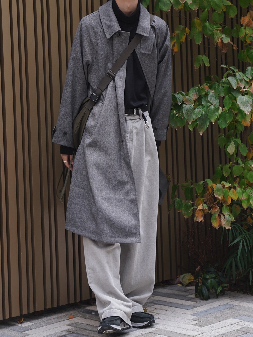 グレー系のステンカラーコート、ブラック系のTシャツ/カットソー、ベージュ系のデニムパンツを着用したメンズの冬コーディネートの5枚目の写真