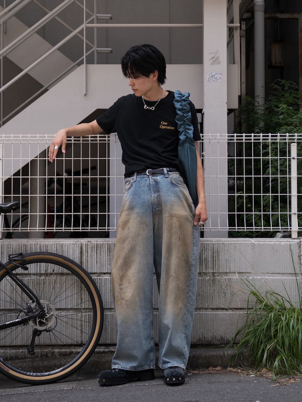 ブルー系のショルダーバッグ、ブラック系のTシャツ/カットソー、ブラック系のブーツを着用したメンズの夏コーディネートの2枚目の写真