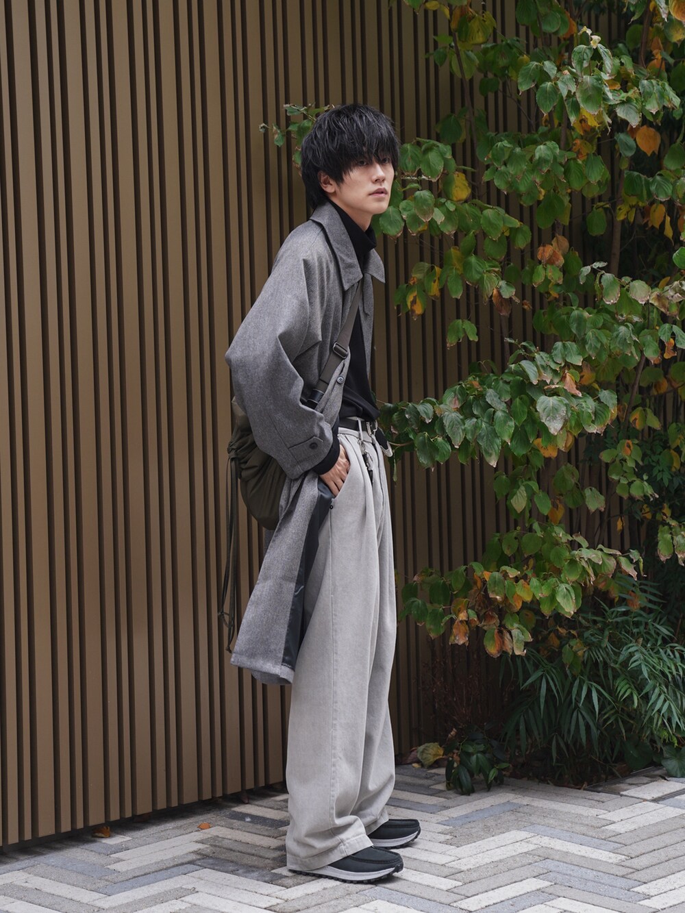 グレー系のステンカラーコート、ブラック系のTシャツ/カットソー、ベージュ系のデニムパンツを着用したメンズの冬コーディネートの2枚目の写真