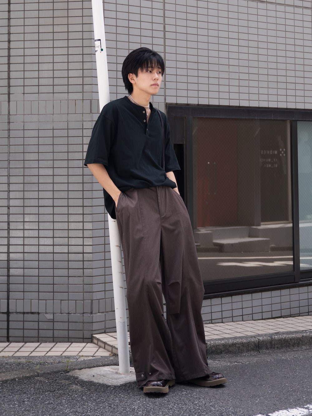 ブラック系のTシャツ/カットソー、ブラウン系のスラックス、ブラウン系のローファーを着用したメンズの夏コーディネートの2枚目の写真