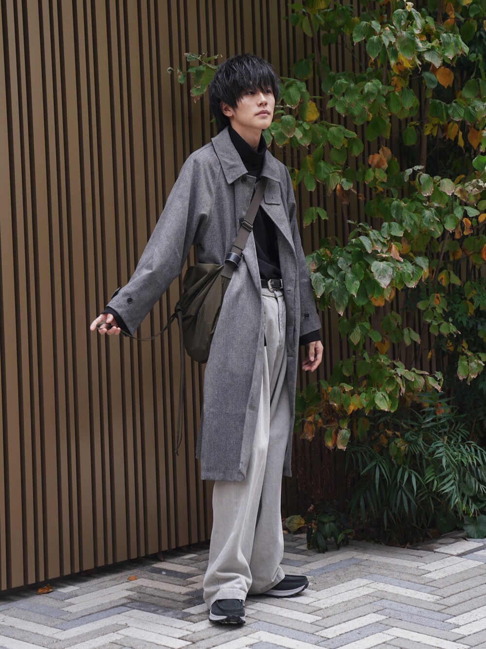 グレー系のステンカラーコート、ブラック系のTシャツ/カットソー、ベージュ系のデニムパンツを着用したメンズの冬コーディネートの4枚目の写真