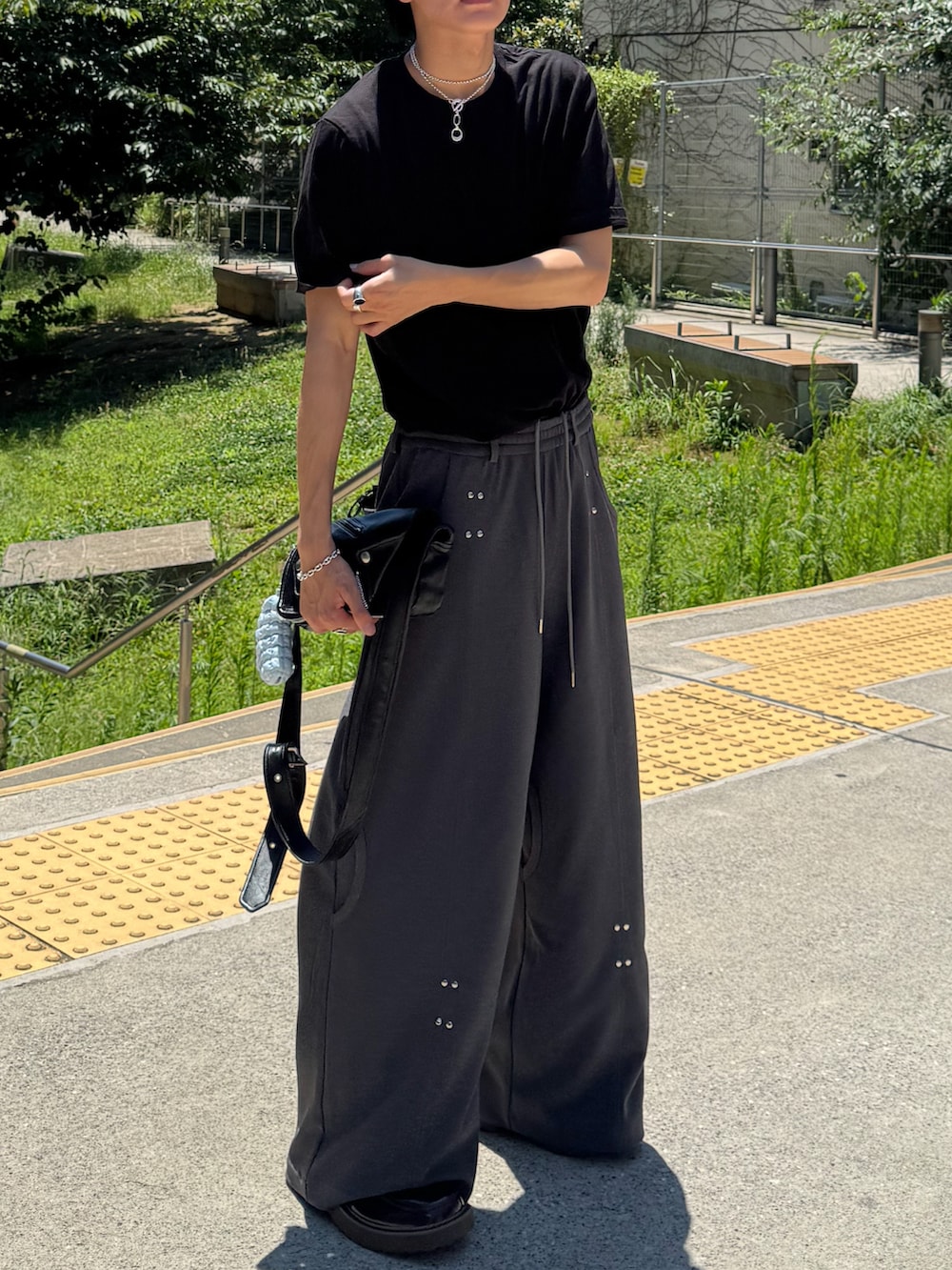 ブラック系のTシャツ/カットソー、ブラック系のショルダーバッグ、ブラウン系のローファーを着用したメンズの夏コーディネートの2枚目の写真