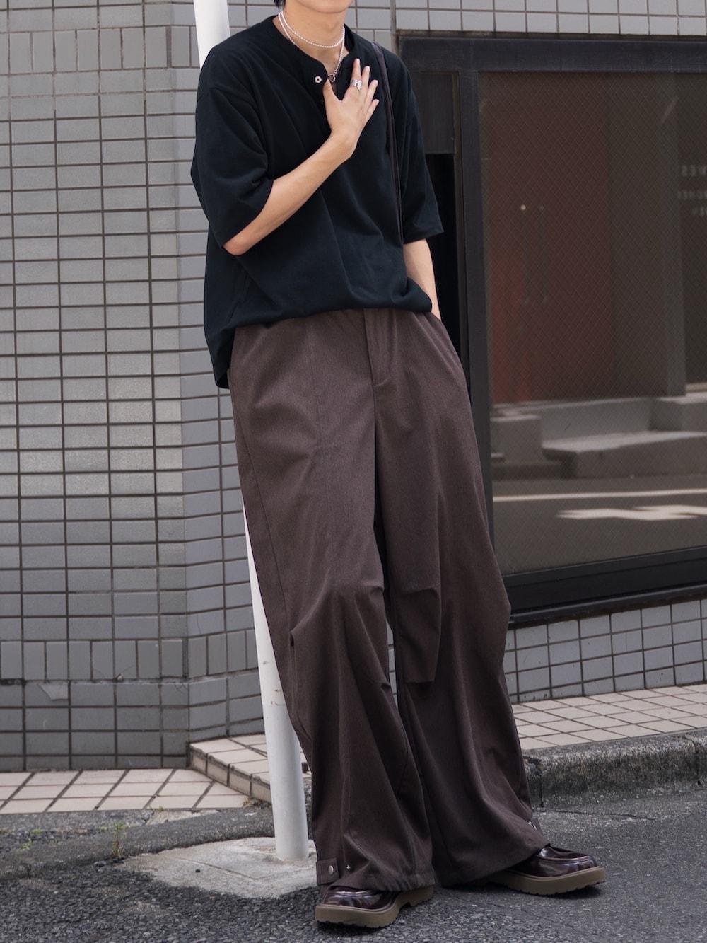 ブラック系のTシャツ/カットソー、ブラウン系のスラックス、ブラウン系のローファーを着用したメンズの夏コーディネートの3枚目の写真