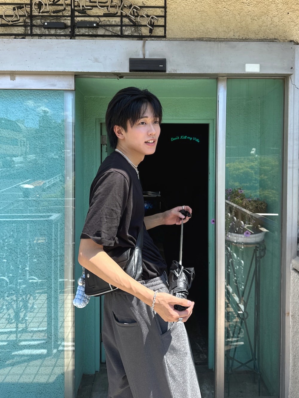 ブラック系のTシャツ/カットソー、ブラック系のショルダーバッグ、ブラウン系のローファーを着用したメンズの夏コーディネートの3枚目の写真